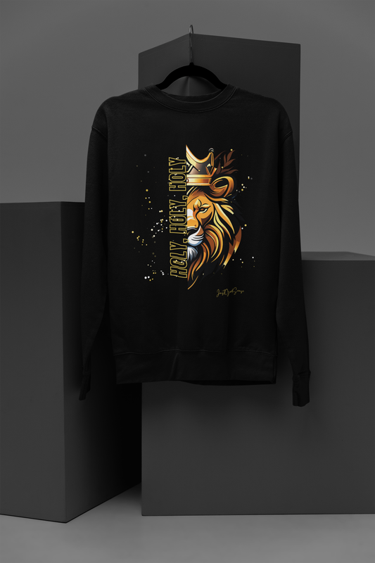 Black crew neck long sleeve sweatshirt with yellow, white, and gold paint splatters mainly on the right side of the background image, and the hollow print message "Holy, Holy, Holy" outlined in yellow running vertically along the left profile image of a lion wearing a crown. JustGodSense signature at the bottom left corner of image.
